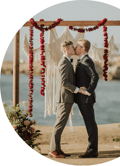 photo of a couple kissing under a wood frame decorated with garlands